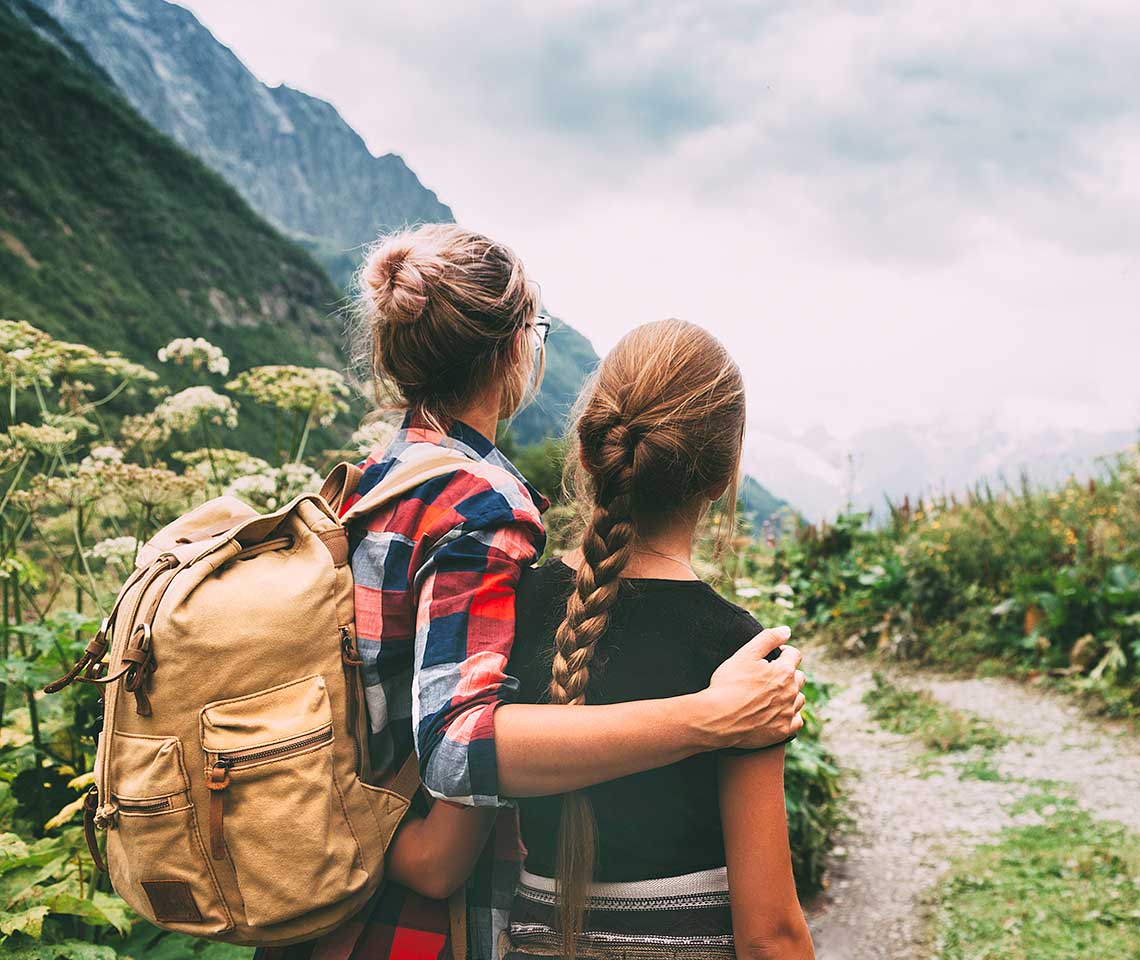 Mom with arm around teen, backpacking on a trail